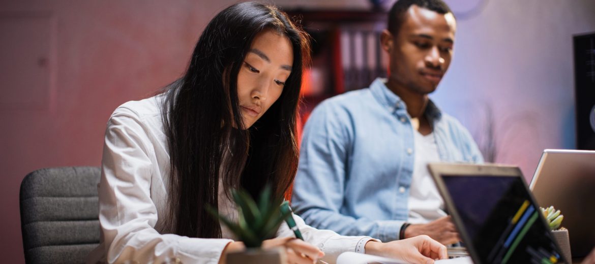 Diverse brokers with gadegts analyzing charts at office